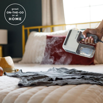 Person using a handheld steamer on a shirt on a bed with text 'great ON-THE-GO or at HOME'.