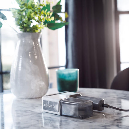 Steamer on a marble surface with a vase and glass in the background