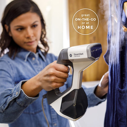 Person using a Steamfast garment steamer on a blue shirt with text 'great ON-THE-GO or at HOME'.