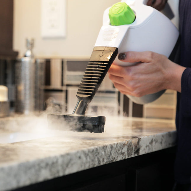Person using a steam cleaner on a kitchen countertop