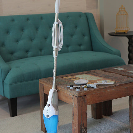 Steam cleaner on a wooden coffee table with a teal sofa and decorative items in the background.