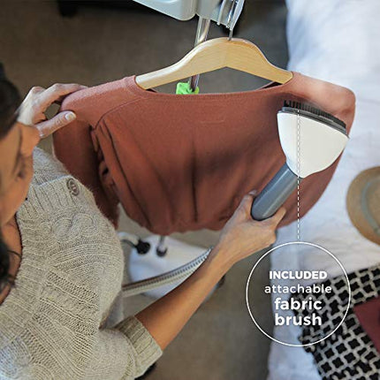 Person using a garment steamer on a brown shirt with an attached fabric brush.