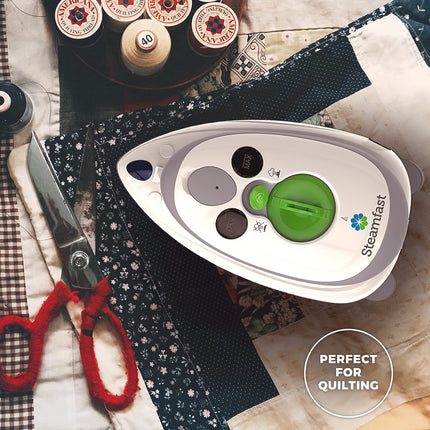 Steamfast iron on a fabric background with scissors and thread spools.