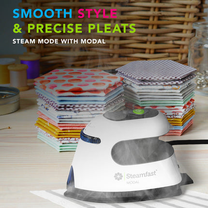 Steam iron with fabric stacks on a table, featuring Steamfast branding.
