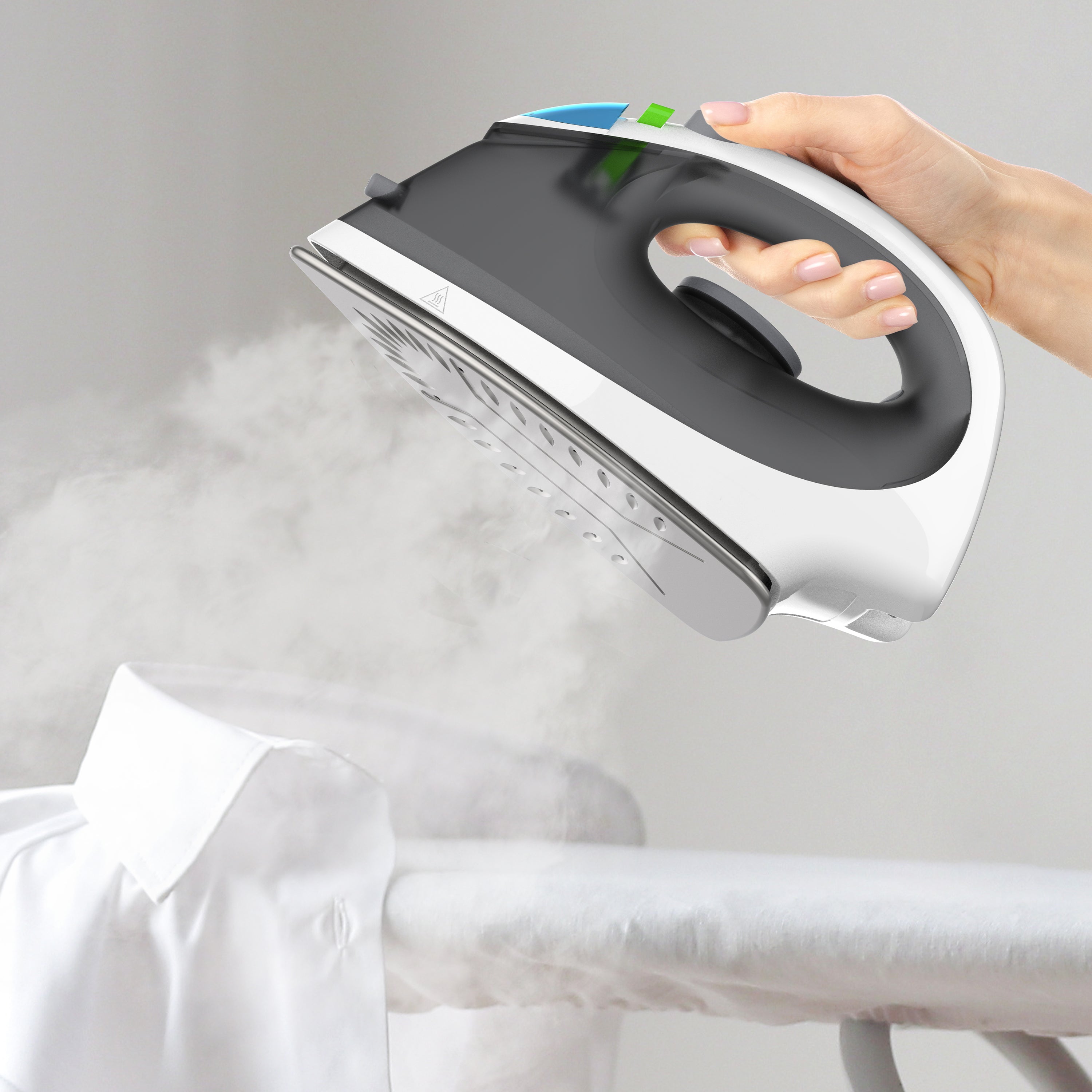 Hand holding a steam iron over a shirt on an ironing board with steam rising.