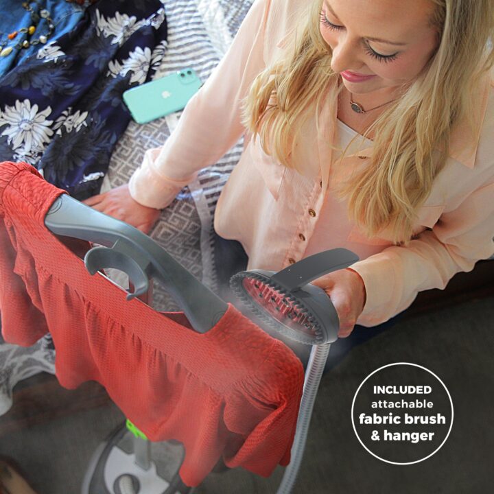 Woman using a SF-562 Canister Fabric Steamer on a dress. Included attachable fabric brush and hanger.