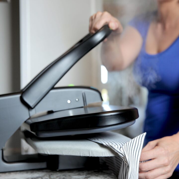 Woman using a SF-623 Mid-Size Fabric Steam Press on a dress shirt.