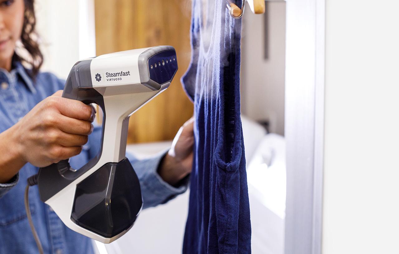 Woman using a handheld Virtuoso steamer on a shirt